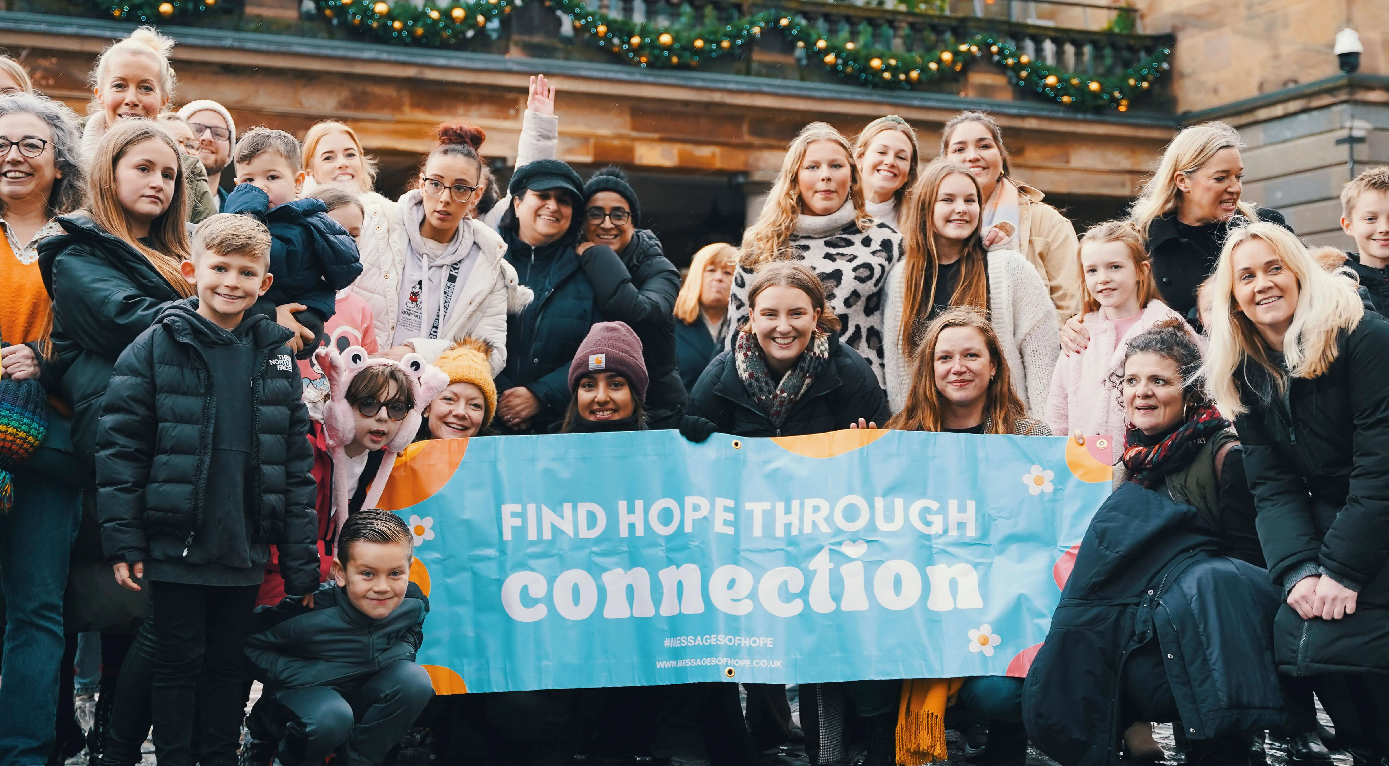 A large group of Hope Bags supporters of all ages gathered behind a banner reading 'Find hope through connection' for the Connections 2024 event